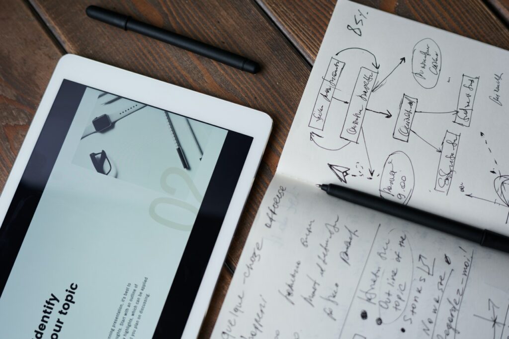 Sketch book next to tablet with marketing plan scribbled in notes.